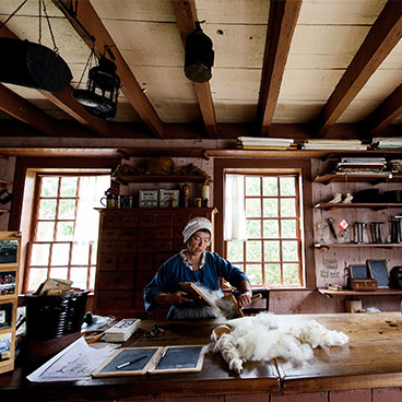 Store Clerk carding wool by hand.